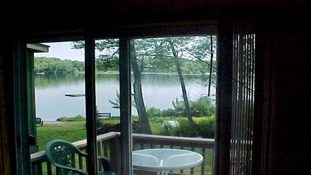 A room with a view of a lake, a table, and a chair. - 4 Season Secluded Lakefront Home near Ski Mountains  (Mt Holly)