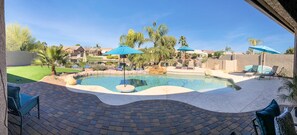 A swimming pool with lounge chairs and umbrellas, surrounded by palm trees and a brick patio. - Resort Living! Quiet Lakefront Home. Pool, large shaded patio, fishing, sleeps 9 (Chandler)