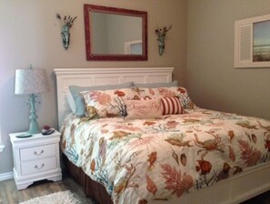 Une chambre à coucher comprenant un lit, une table de chevet, une lampe, un miroir et des éléments de décoration murale.