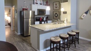 A kitchen with a central island, stainless steel appliances, and a seating area with stools. -  Village by the Beach!Townhome Walking distance to the BEACH, Heated Resort Pool (Corpus Christi)