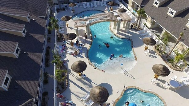 A resort with two swimming pools, sun loungers, umbrellas, and a small water slide. -  Village by the Beach!Townhome Walking distance to the BEACH, Heated Resort Pool (Corpus Christi)