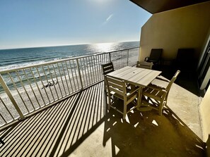 Een balkon met een tafel en stoelen, met uitzicht op de oceaan.