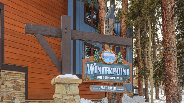 Un edificio de madera con base de piedra y un letrero que dice 'Winterpoint 200 Primrose Path'.