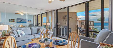 Sala de estar moderna com área de jantar, janelas amplas e varanda com vista para o oceano.