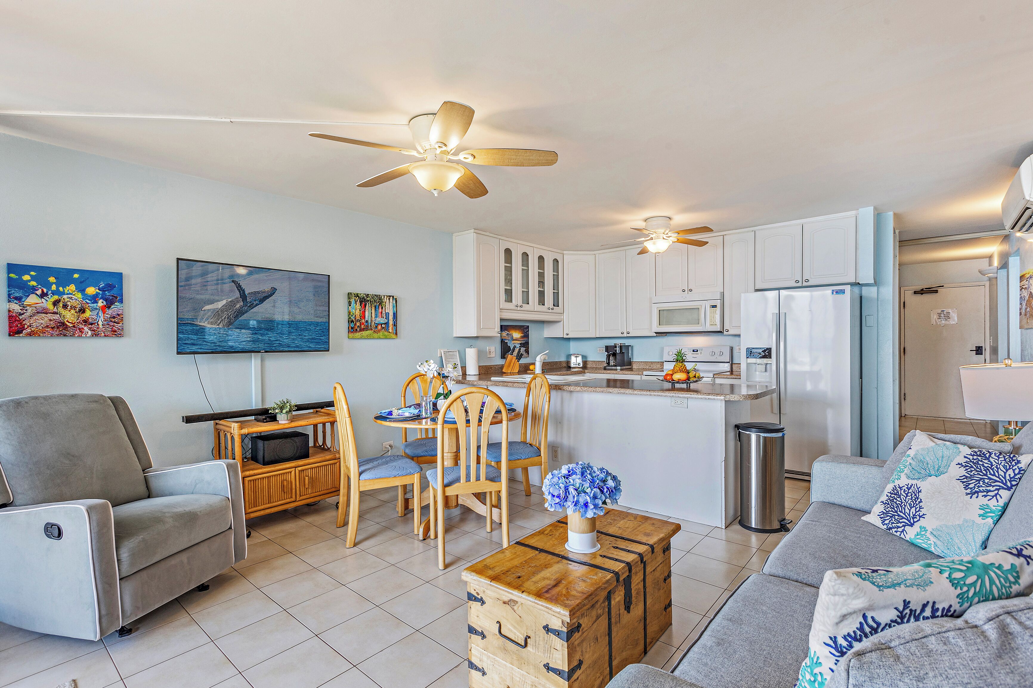 A modern living room with a sofa, a dining table with chairs, a wooden coffee table, and a kitchen area with cabinets and appliances.
