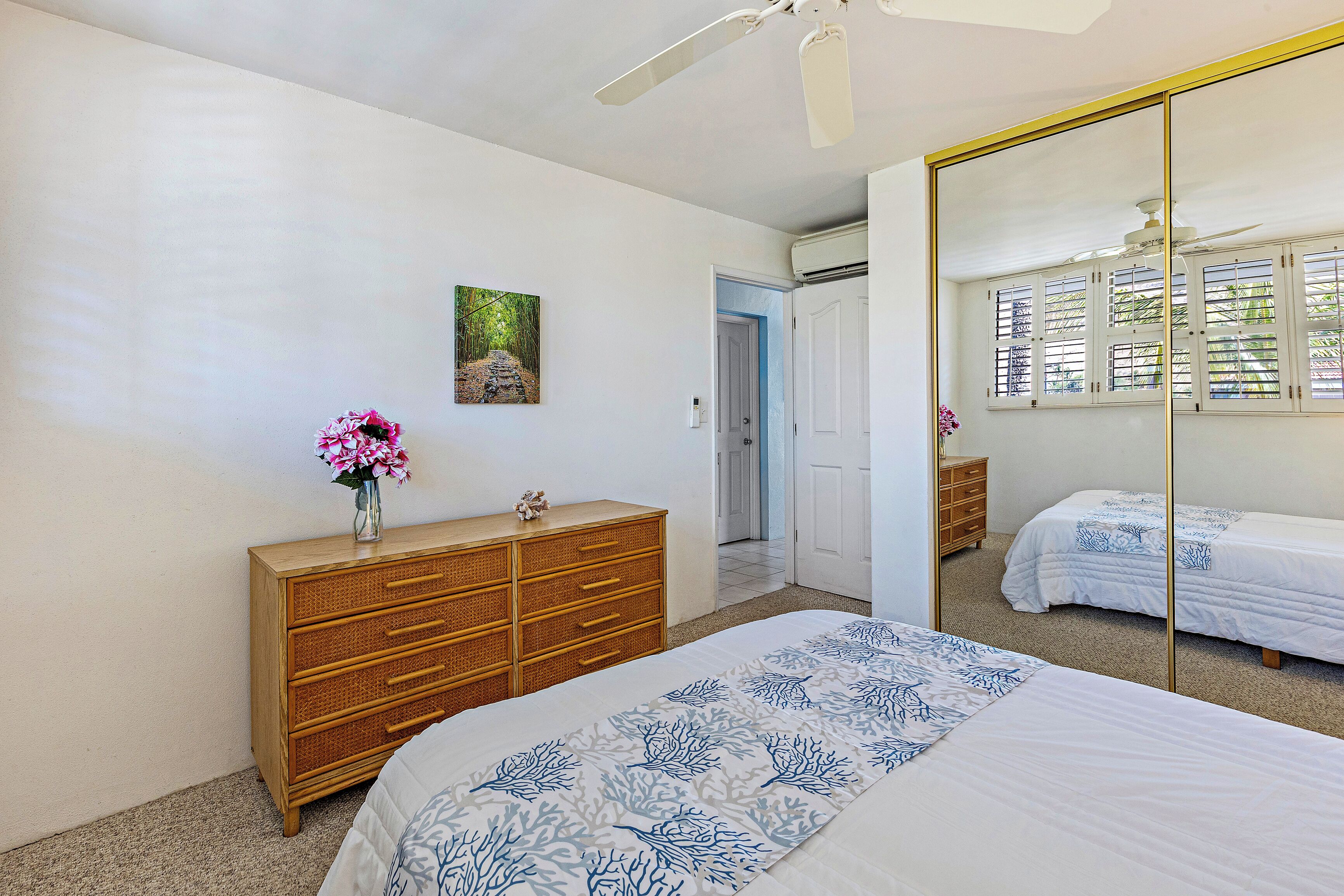 Une chambre à coucher avec un lit, une commode, un miroir et une fenêtre avec des stores.