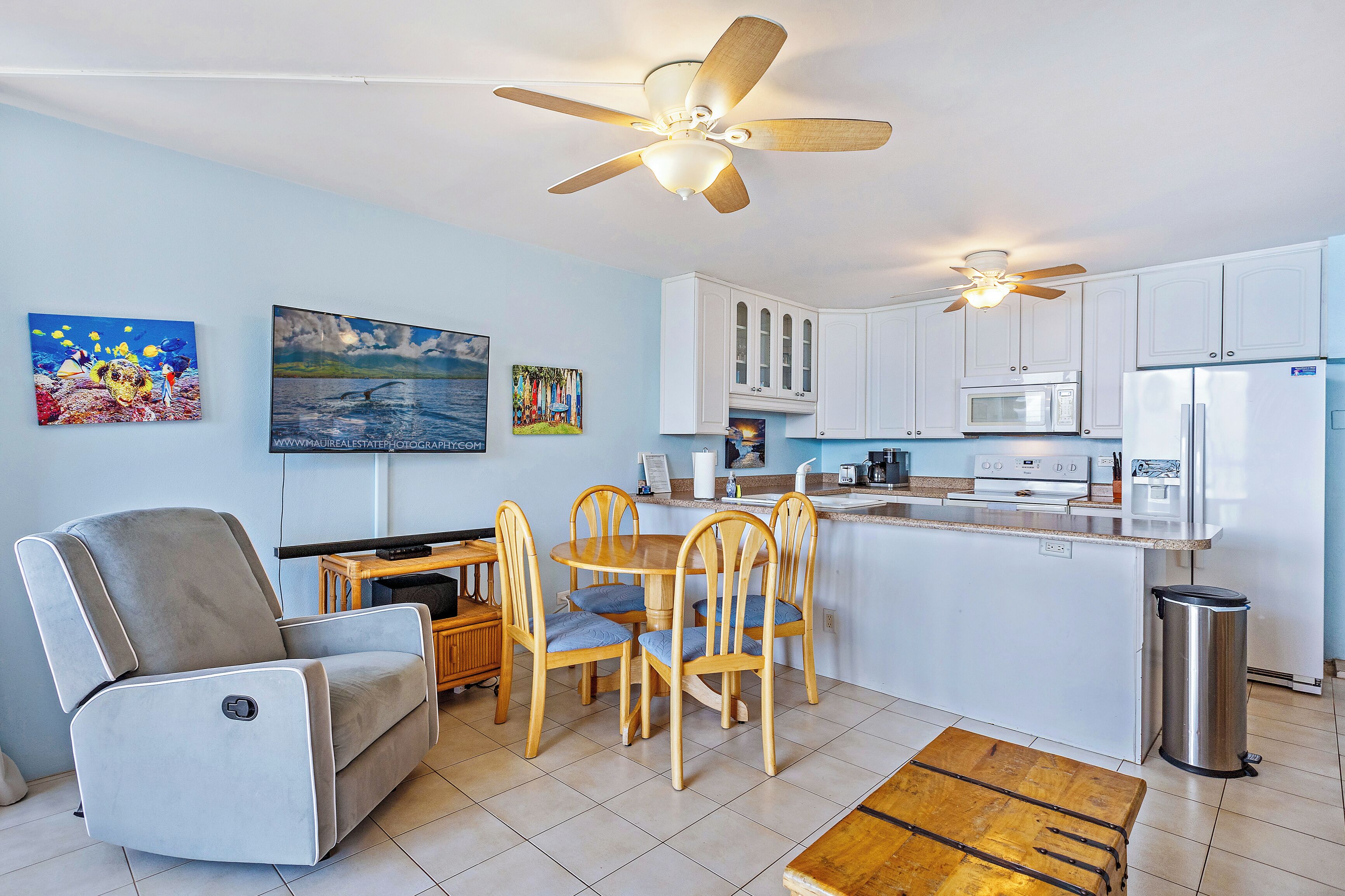 A modern kitchen with white cabinets, a central island, and a ceiling fan.