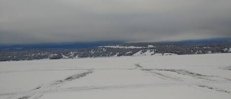 A snow-covered landscape with a flat terrain and distant trees.