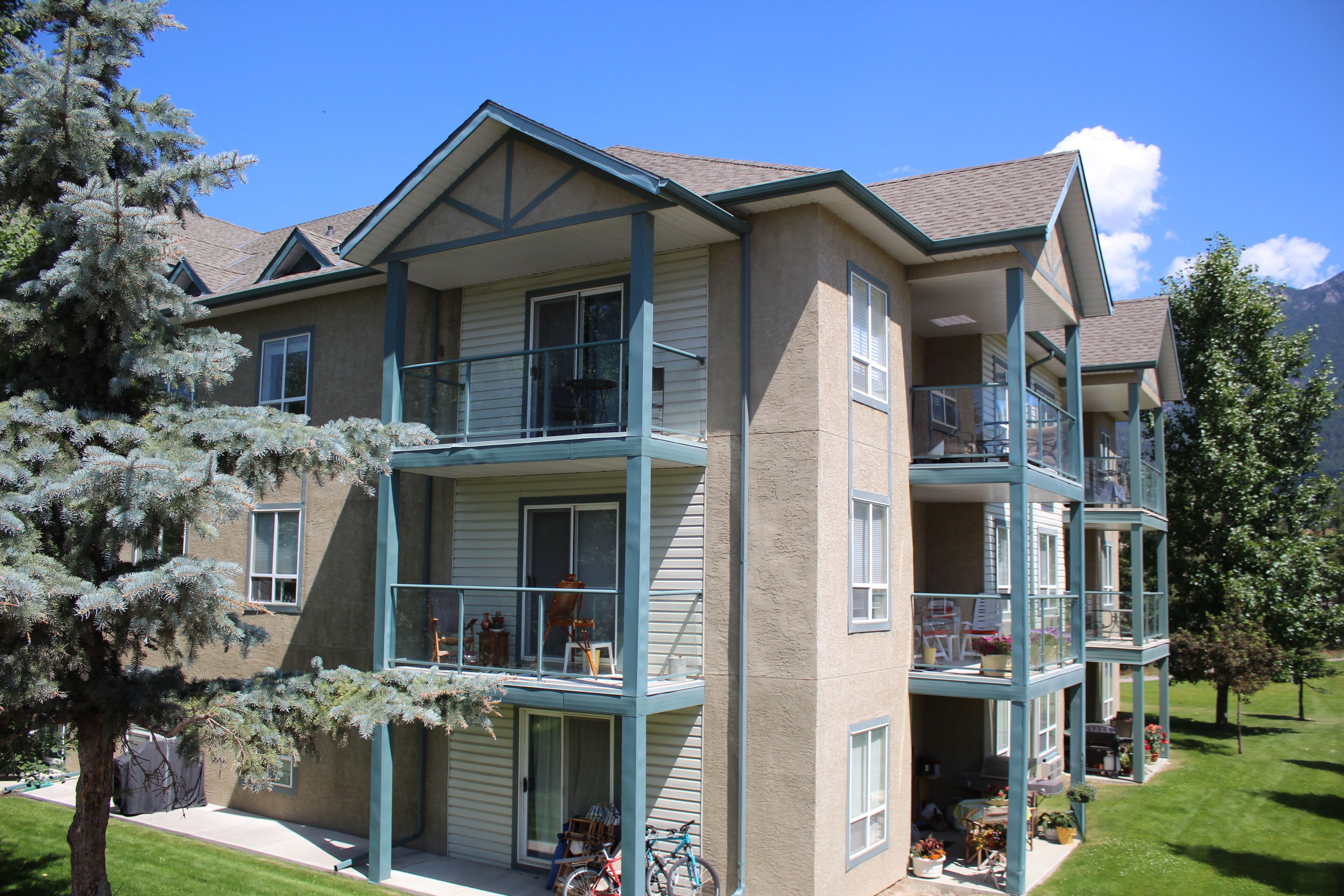 A multi-story building with balconies, a covered front porch, and a well-maintained lawn.