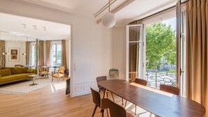 A spacious living area with a wooden floor, a large dining table, and a sofa.