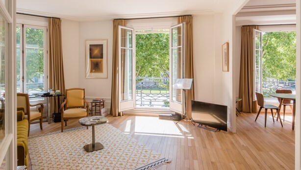 A spacious living room with a fireplace, a sofa, a coffee table, and a dining area with chairs.