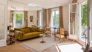 A well-lit living room with a yellow sofa, a coffee table, and a dining area with chairs.