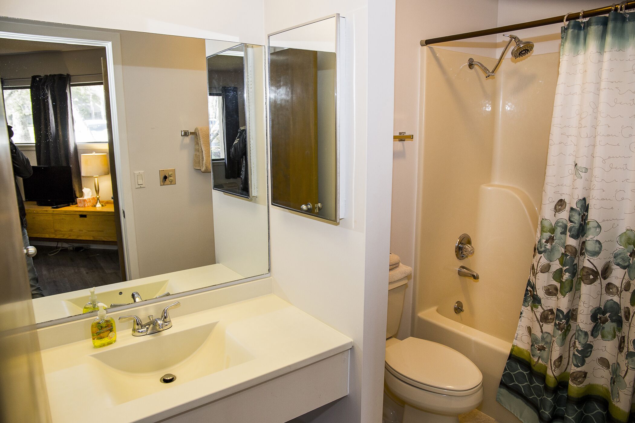 A bathroom with a sink, mirror, toilet, and shower.