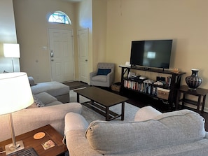 A living room with a sofa, coffee table, TV, bookshelf, and a lamp.