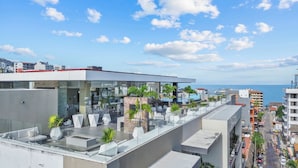 Eine Dachterrasse mit moderner Sitzgelegenheit, einem Pool und Blick auf das Meer.