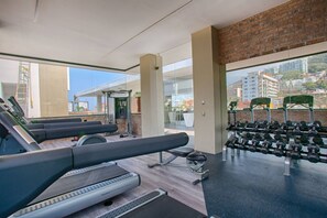 Une salle de sport équipée de tapis de course, d’haltères et d’un banc de musculation.