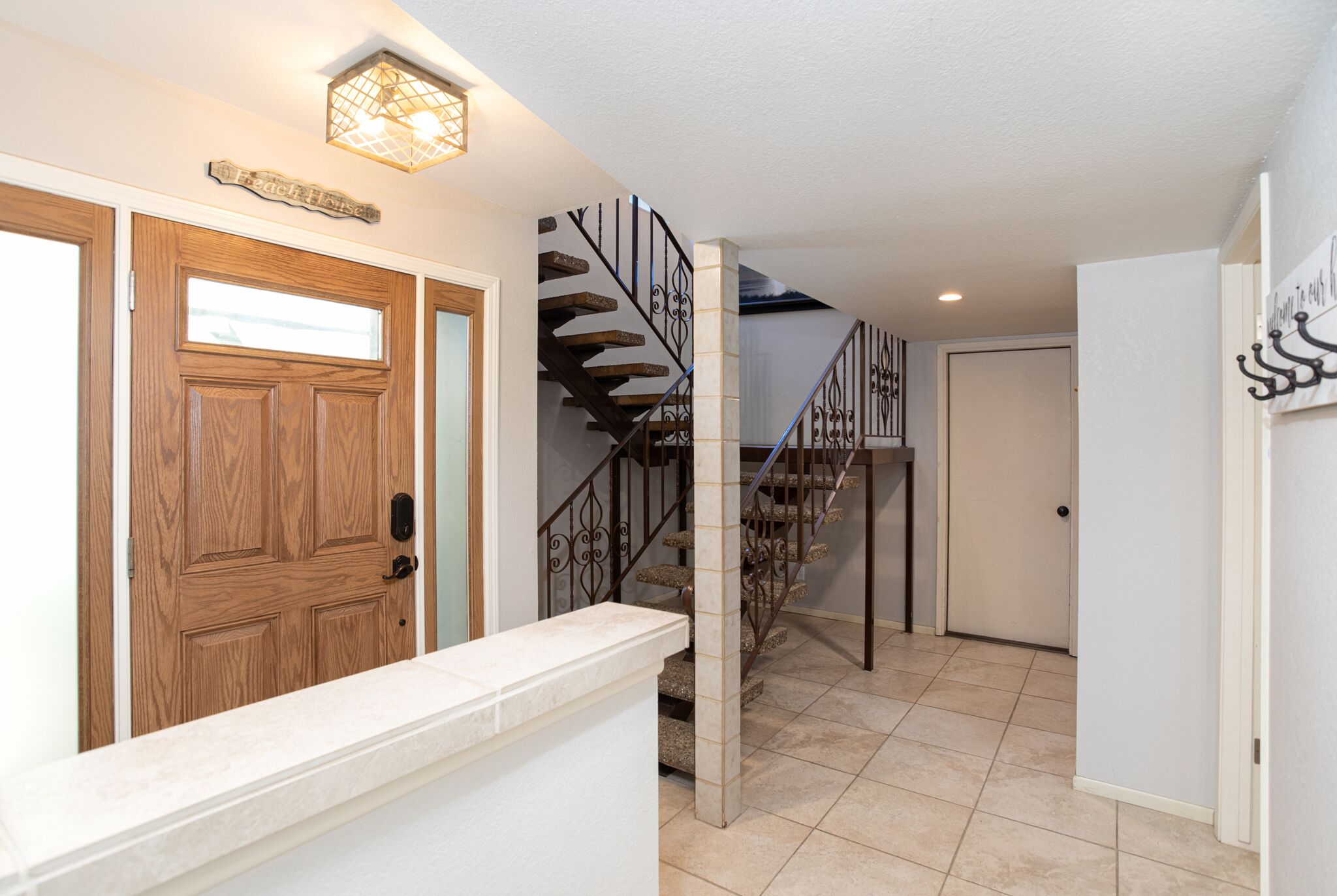 A wooden door with a glass panel, a staircase with metal railings, and a light fixture above the door.