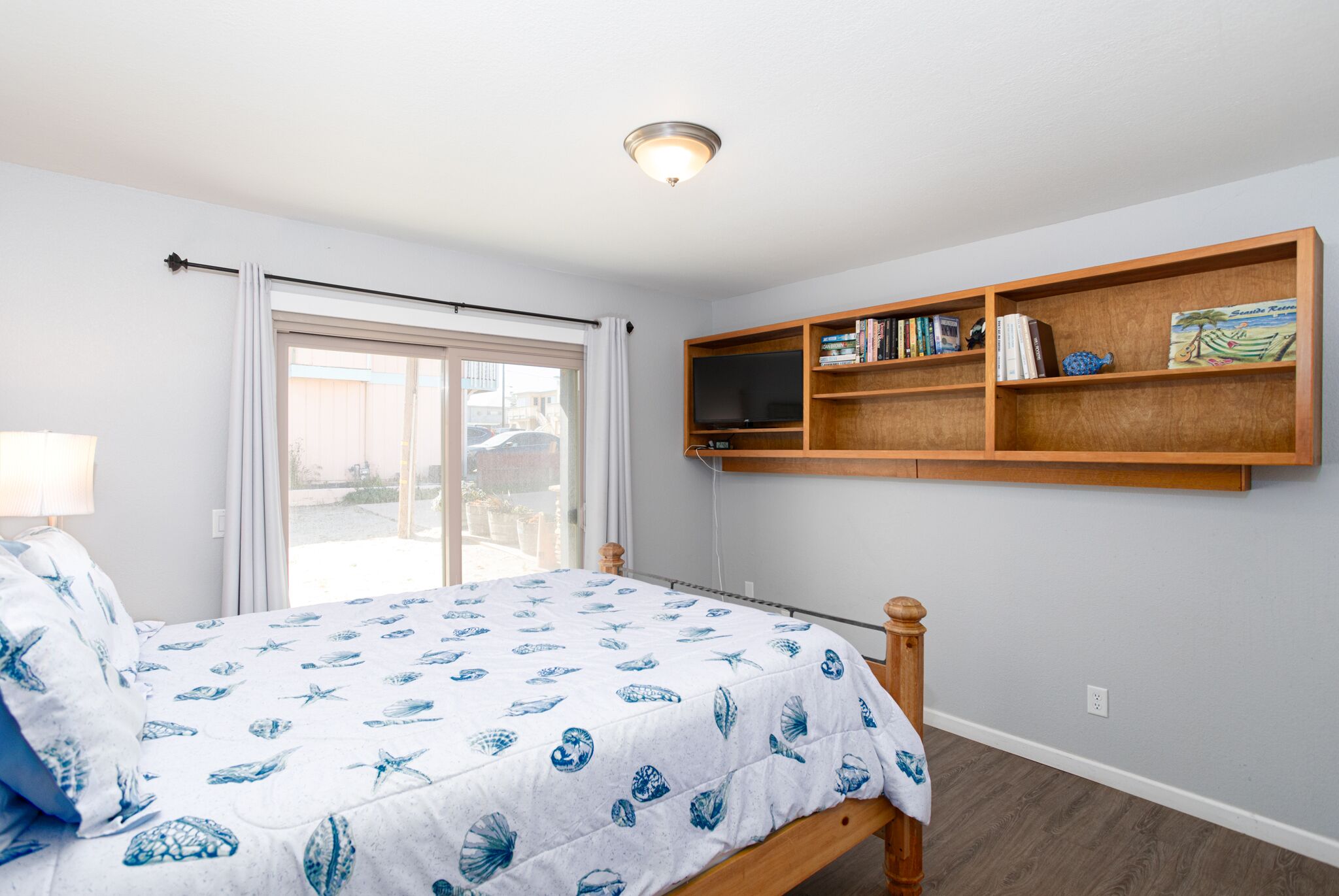 A bedroom with a bed, a bookshelf, a window, and a ceiling light.