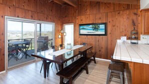 A wooden interior with a dining area, a kitchen counter, and a large window overlooking a scenic landscape.