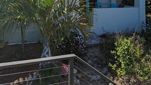 Une maison à deux étages avec un balcon, entourée de verdure et sous un ciel dégagé.