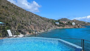 Une piscine avec vue sur la mer et les collines.