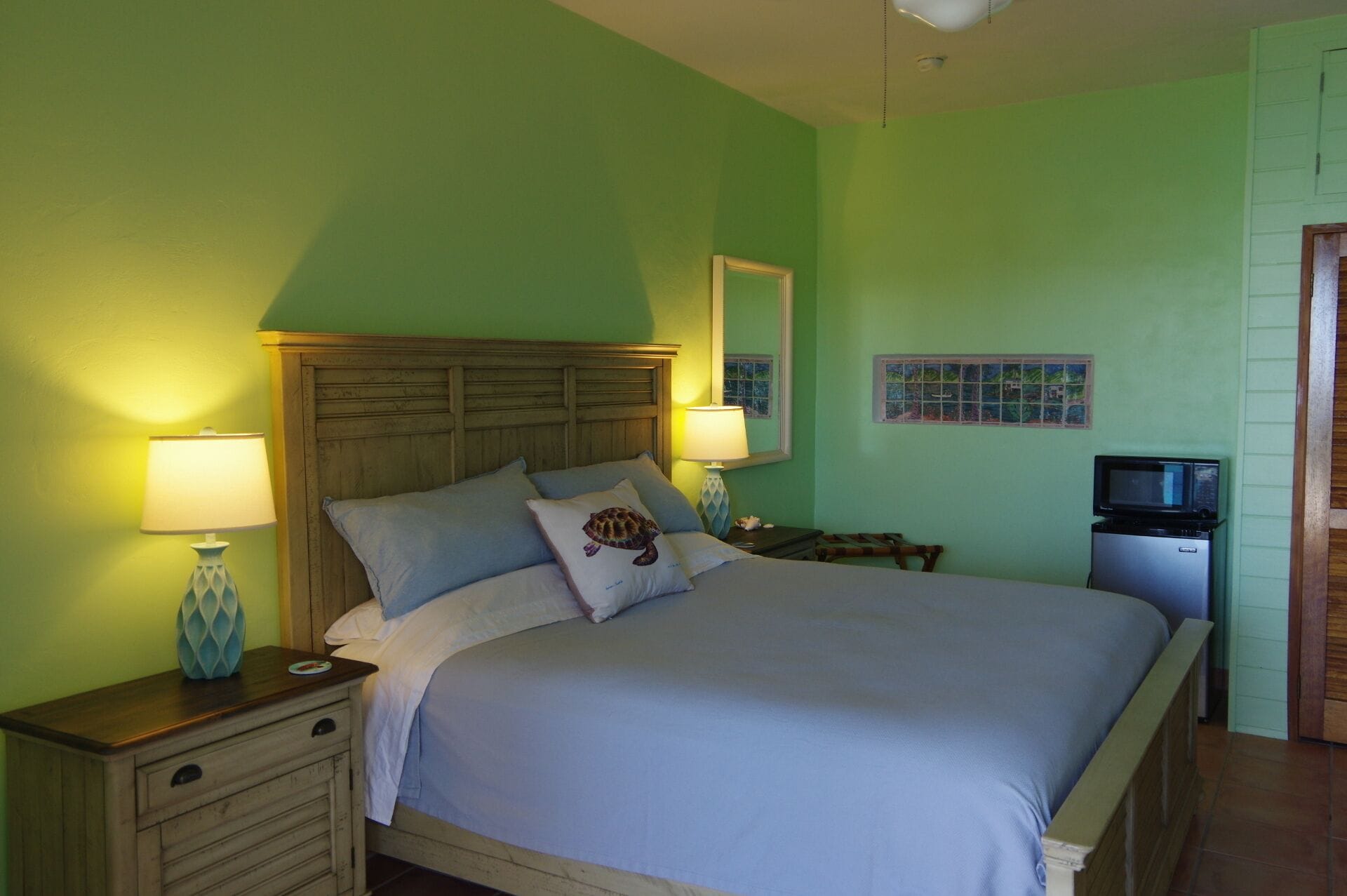 Une chambre à coucher comprenant un lit, des tables de chevet, un téléviseur et un mur orné d’un tableau encadré.