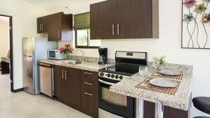 Une cuisine dotée de meubles en bois foncé, d’appareils électroménagers en acier inoxydable, d’un plan de travail en granit et d’un coin repas avec une table et des chaises.