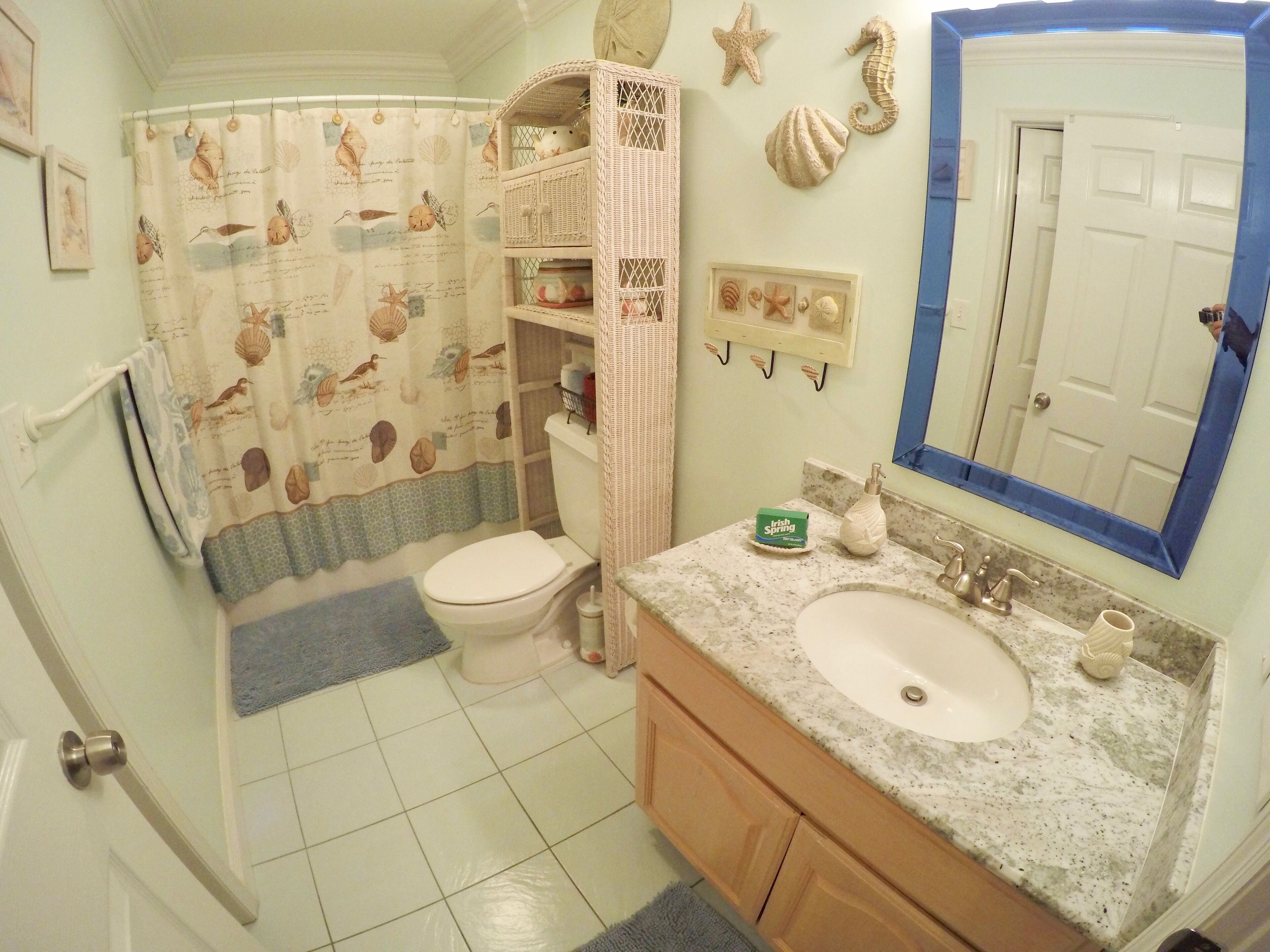 Un baño con inodoro, lavamanos y cortina de ducha con diseños de criaturas marinas.