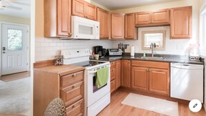 A modern kitchen with wooden cabinets, a white stove, a microwave, and a dishwasher.