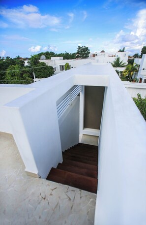 Un edificio blanco con una escalera que lleva a un espacio cubierto.