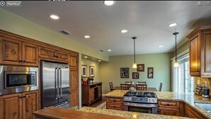 A kitchen with wooden cabinets, stainless steel appliances, granite countertops, and pendant lighting.