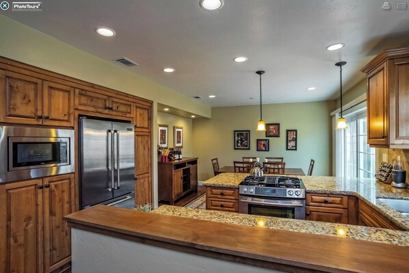 A kitchen with wooden cabinets, stainless steel appliances, granite countertops, and pendant lighting.