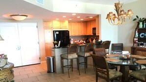 Una cocina moderna con armarios blancos, un refrigerador negro y una zona de comedor con sillas de madera y una mesa redonda.