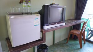 Une petite cuisine équipée d’un réfrigérateur, d’un four à micro-ondes et d’une télévision posée sur une table en bois.