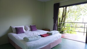 Un lit avec une literie blanche et violette, une tête de lit rose et une vue sur la verdure par la fenêtre.