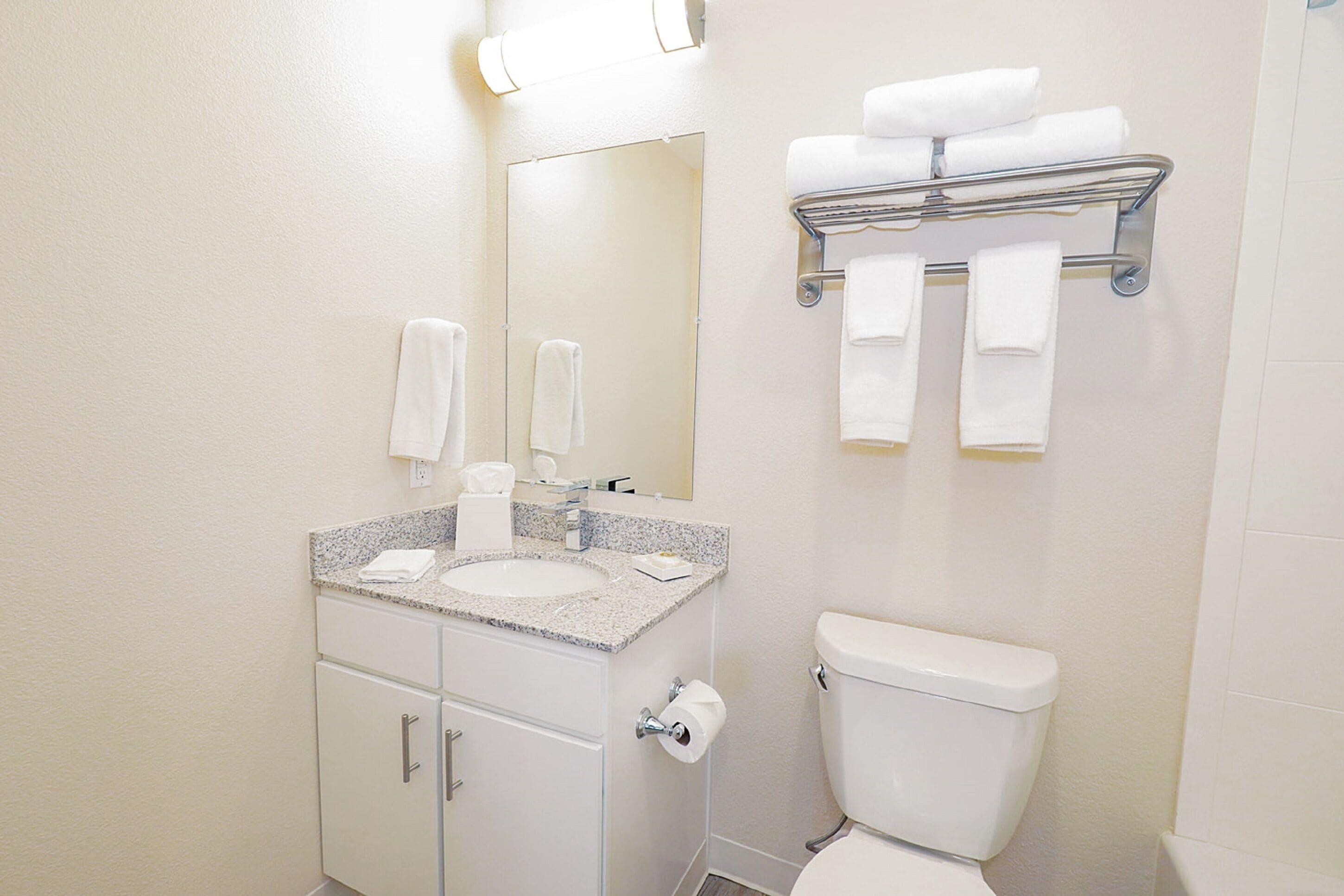 A bathroom with a sink, mirror, toilet, and towel rack.