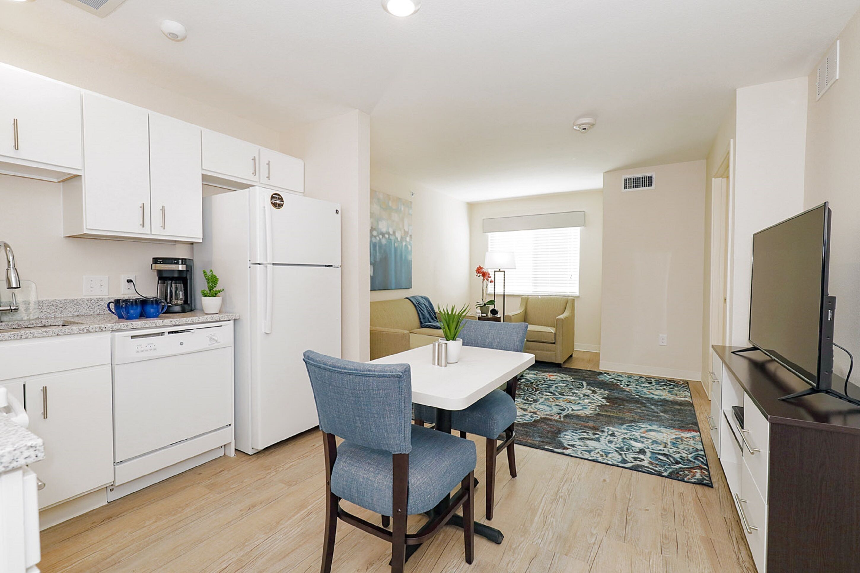 Un espace de vie compact comprenant une kitchenette, un coin repas et un téléviseur.