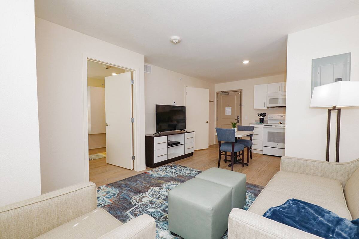 A modern apartment with a living room, kitchenette, and a dining area.