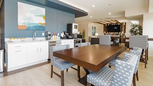 A modern kitchen with white cabinets, a large island, and blue patterned chairs. - Parks Residential -Richardson (Richardson)
