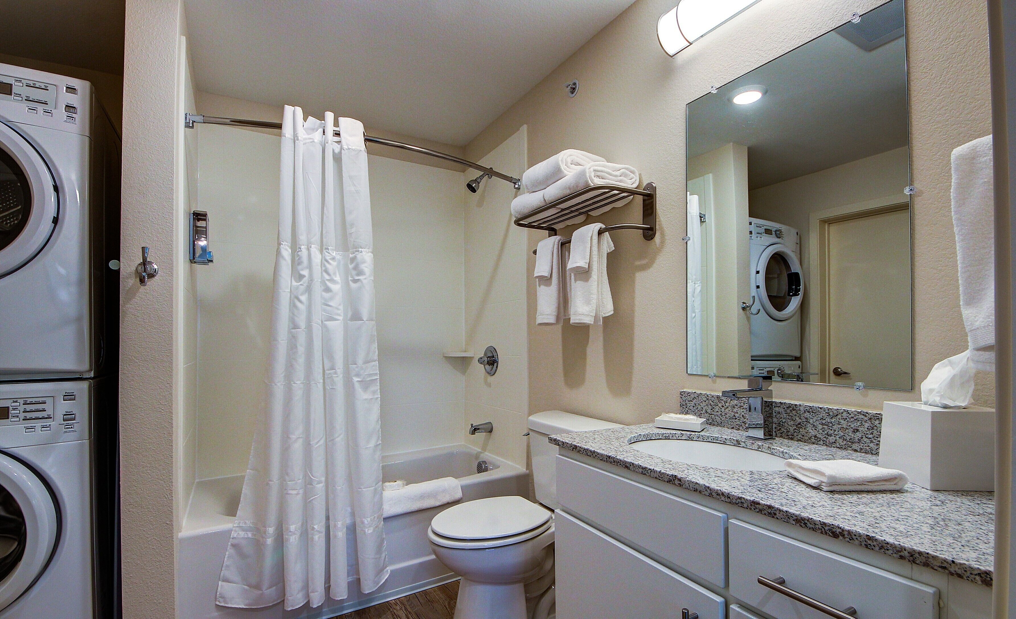 A bathroom with a shower, toilet, and a washing machine.