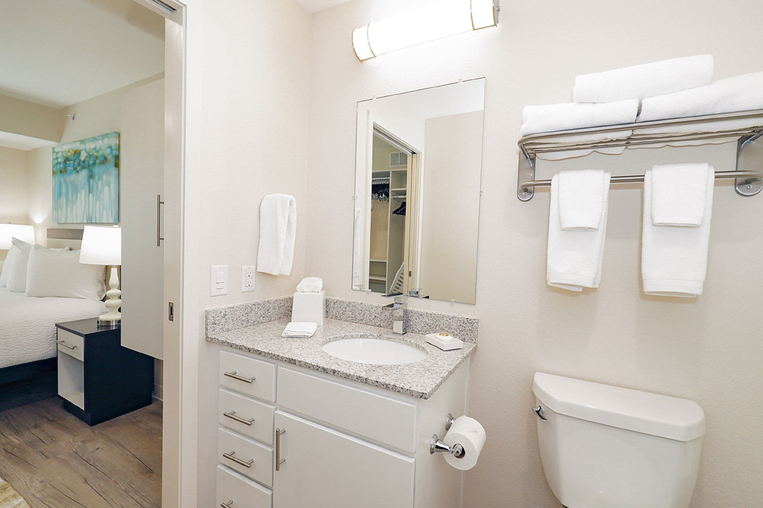 A hotel bathroom with a sink, toilet, and towel rack.