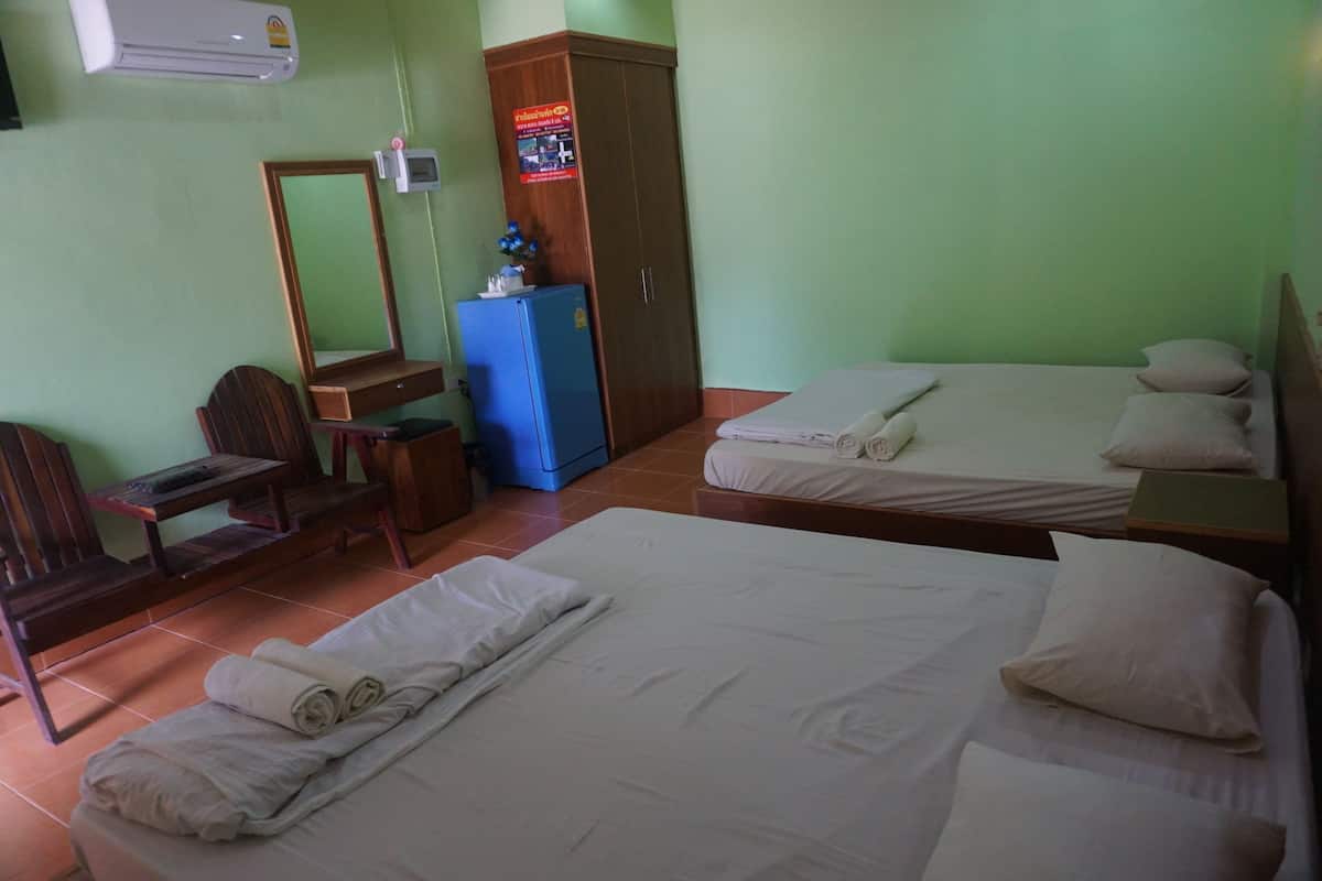 A hotel room with two beds, a desk, a chair, a wardrobe, and an air conditioning unit.