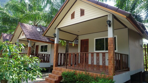 A bungalow with a tiled porch, a satellite dish, and a staircase leading to the entrance.