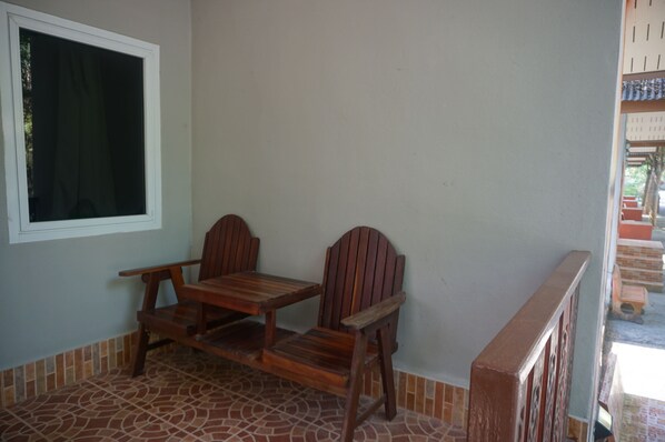 A patio with a wooden table and chairs, a window, and a tiled floor.