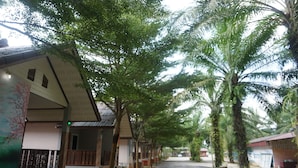 A row of traditional-style buildings with a covered walkway, surrounded by lush greenery and palm trees.