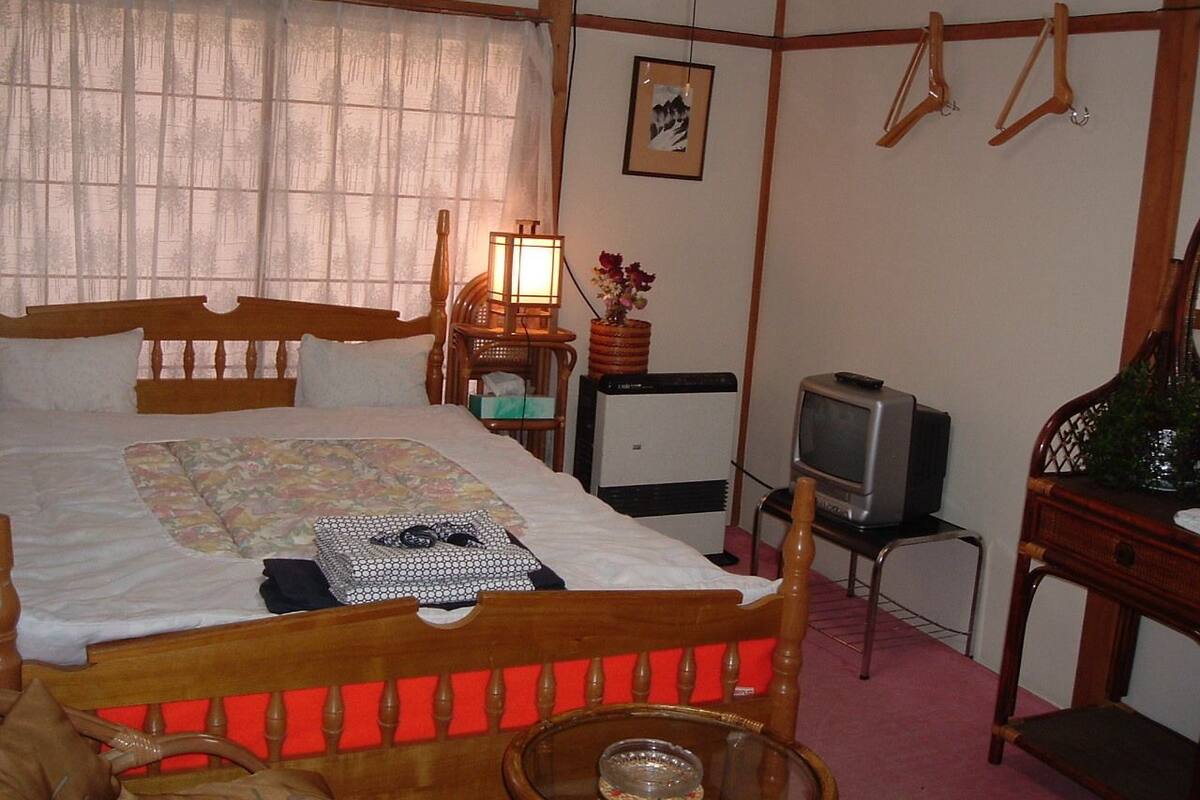 A bedroom with a wooden bed, a television, a lamp, and a small table.