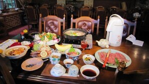 Une table à manger avec différents plats, une théière et un récipient pour servir des plats chauds.