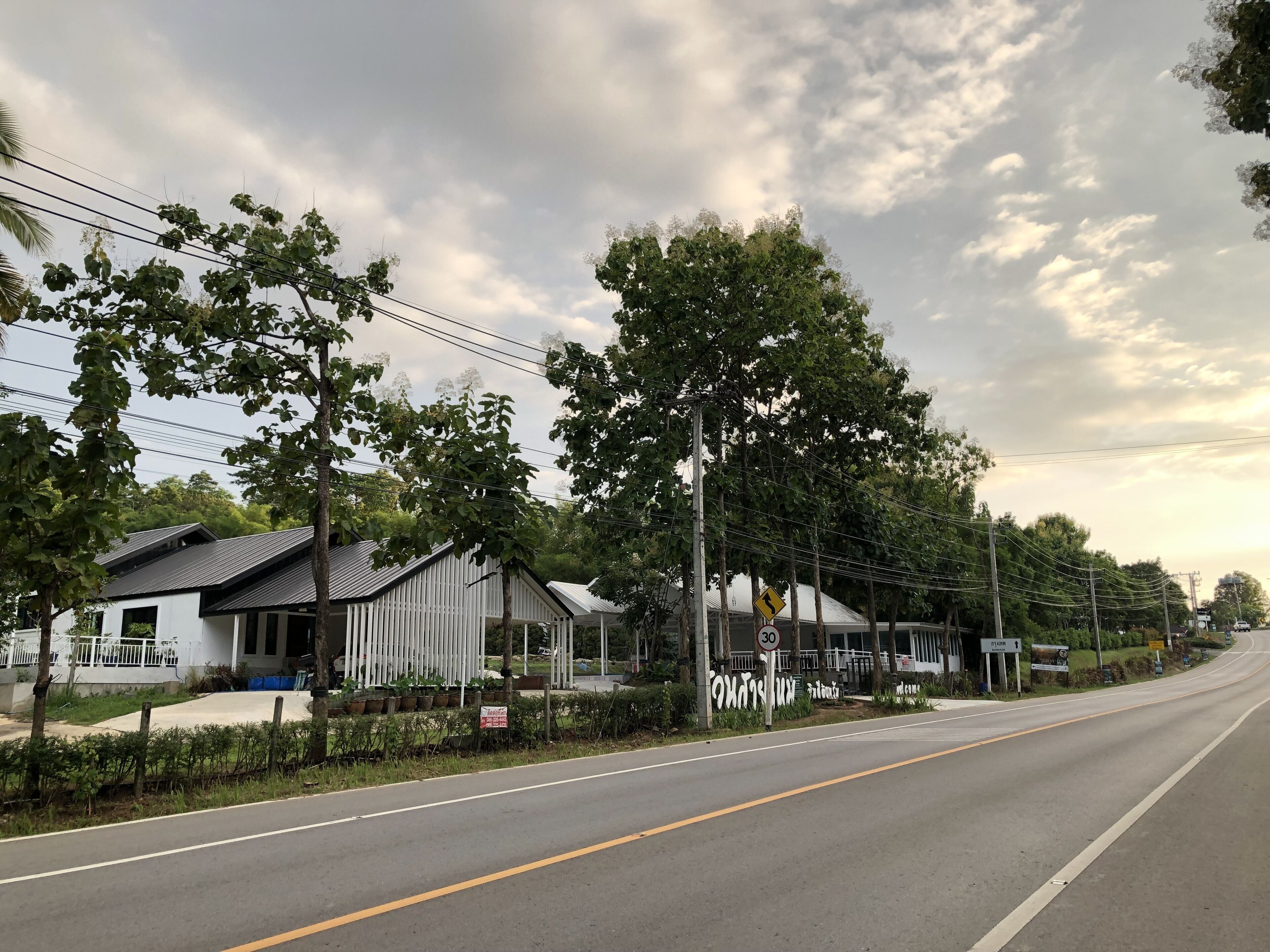 A road with a speed limit sign of 30 km/h, a left turn warning sign, and a sign indicating a rest area.