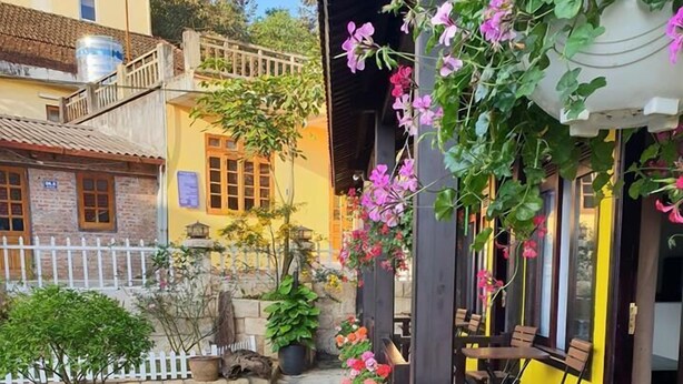 Un sendero bordeado de flores coloridas que lleva a un edificio con terraza.