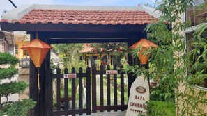 A gated entrance with a tiled roof, a signboard, and a potted plant.